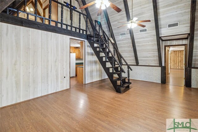 unfurnished living room with wood-type flooring, high vaulted ceiling, wooden walls, and beamed ceiling