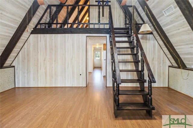 stairway with wood-type flooring, vaulted ceiling with beams, wood ceiling, and wood walls