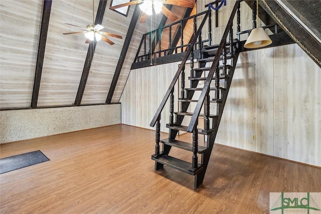 staircase with wood-type flooring, lofted ceiling with beams, and ceiling fan