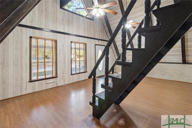 staircase with hardwood / wood-style flooring, high vaulted ceiling, and ceiling fan