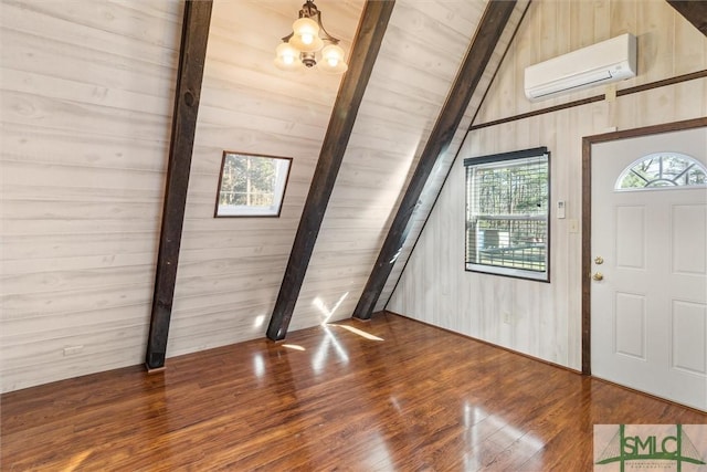 entryway with an inviting chandelier, lofted ceiling with beams, an AC wall unit, wooden walls, and dark hardwood / wood-style flooring