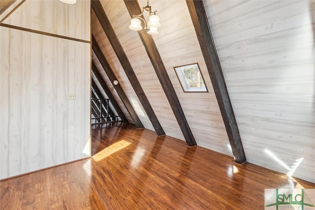 bonus room featuring a notable chandelier, hardwood / wood-style flooring, wooden walls, and lofted ceiling with beams