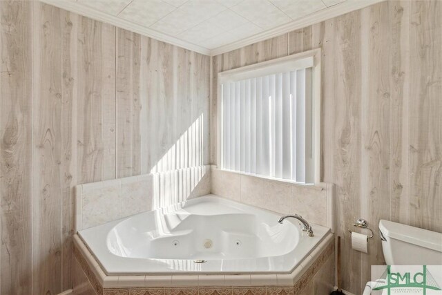 bathroom with tiled tub, crown molding, and toilet