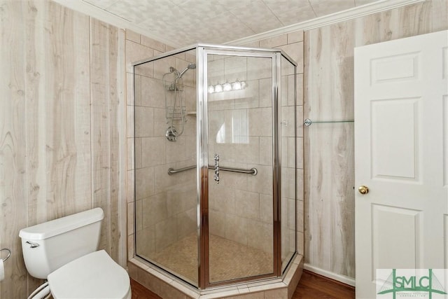 bathroom with toilet, crown molding, and a shower with shower door