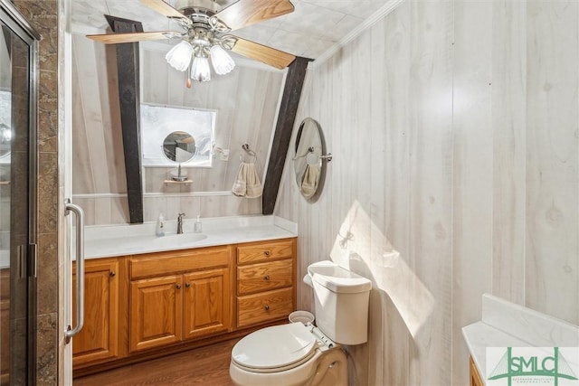 bathroom with hardwood / wood-style floors, a shower with shower door, vanity, ceiling fan, and toilet