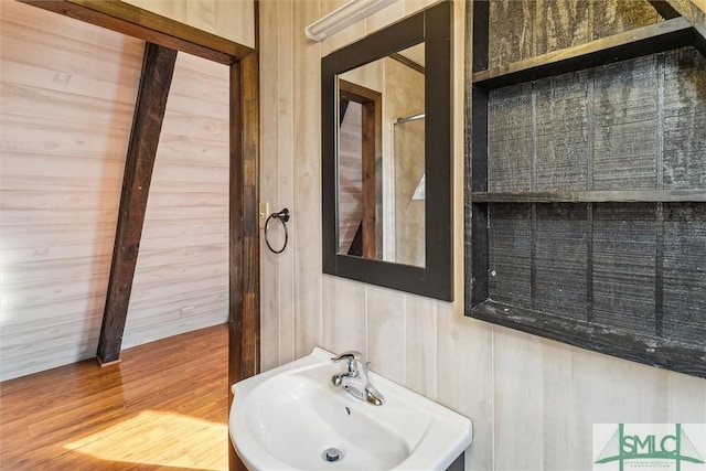 bathroom with sink, wood-type flooring, and wood walls