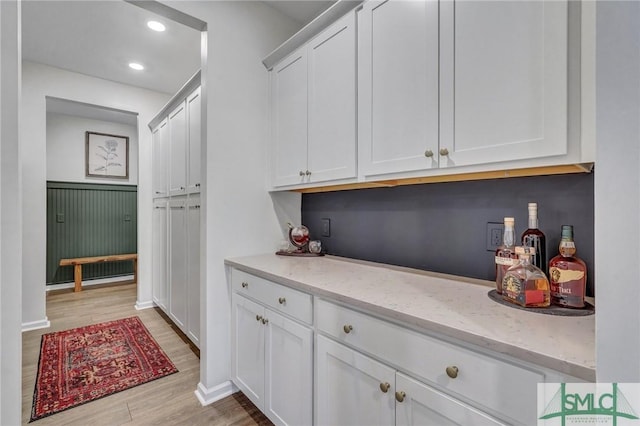 interior space with light stone counters, white cabinets, and light wood-type flooring