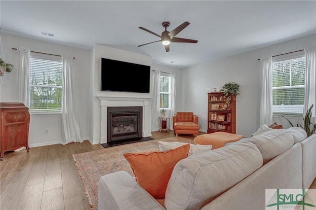 living room with light hardwood / wood-style flooring, a wealth of natural light, and ceiling fan