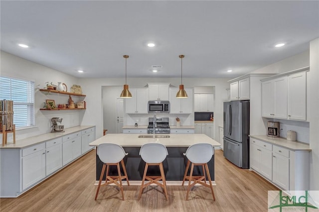 kitchen with pendant lighting, a breakfast bar, appliances with stainless steel finishes, light hardwood / wood-style floors, and white cabinetry