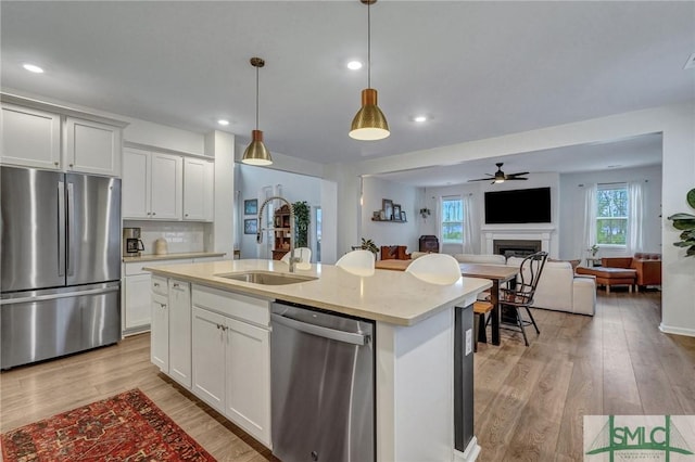 kitchen with a center island with sink, decorative light fixtures, white cabinetry, and stainless steel appliances