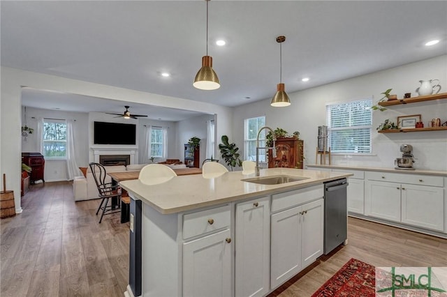 kitchen with light stone countertops, white cabinetry, sink, hanging light fixtures, and a center island with sink