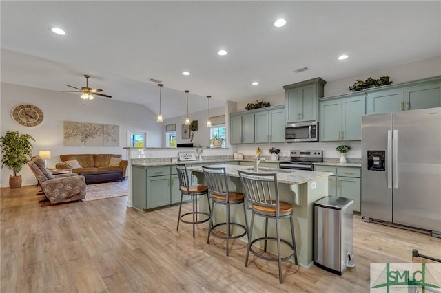 kitchen featuring ceiling fan, stainless steel appliances, backsplash, decorative light fixtures, and a breakfast bar area