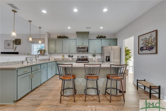 kitchen with pendant lighting, a kitchen island, light stone countertops, and appliances with stainless steel finishes