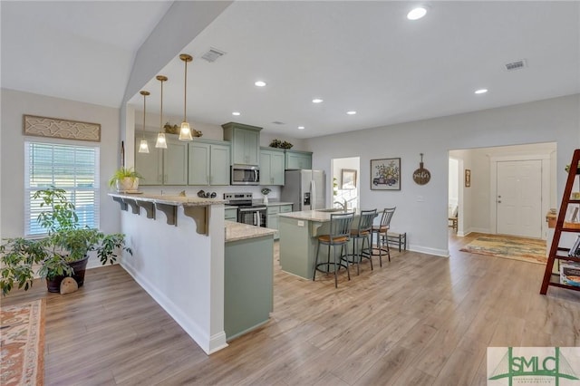 kitchen featuring hanging light fixtures, stainless steel appliances, light stone counters, kitchen peninsula, and a breakfast bar