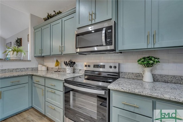 kitchen featuring backsplash, light stone counters, stainless steel appliances, and light hardwood / wood-style flooring