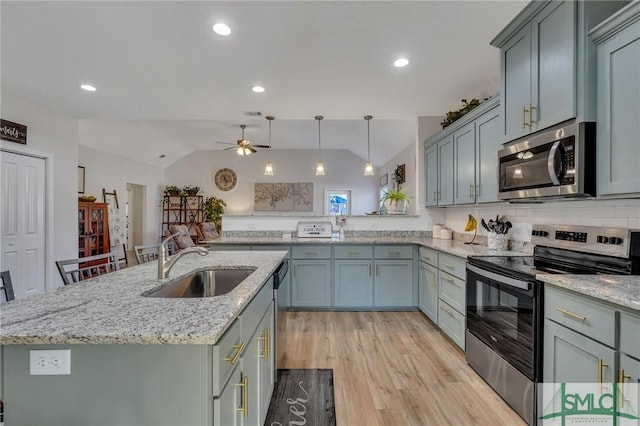 kitchen featuring sink, vaulted ceiling, ceiling fan, an island with sink, and appliances with stainless steel finishes