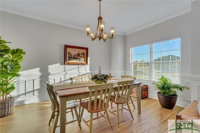 dining space with a notable chandelier, ornamental molding, and light hardwood / wood-style flooring