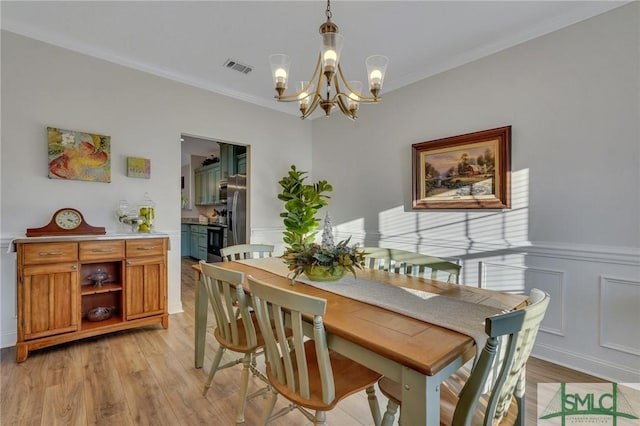 dining room featuring a notable chandelier, light hardwood / wood-style floors, and ornamental molding