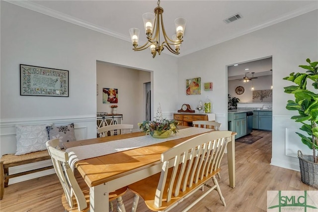 dining area featuring ceiling fan with notable chandelier, light wood-type flooring, and crown molding