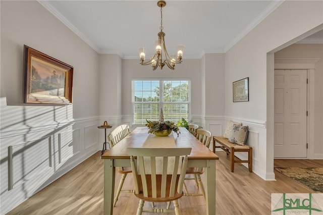 dining room featuring a chandelier, light wood-type flooring, and crown molding