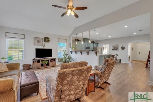 living room featuring light wood-type flooring, vaulted ceiling, and ceiling fan