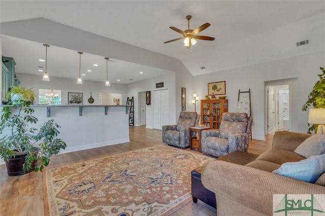 living room with ceiling fan, vaulted ceiling, and light wood-type flooring