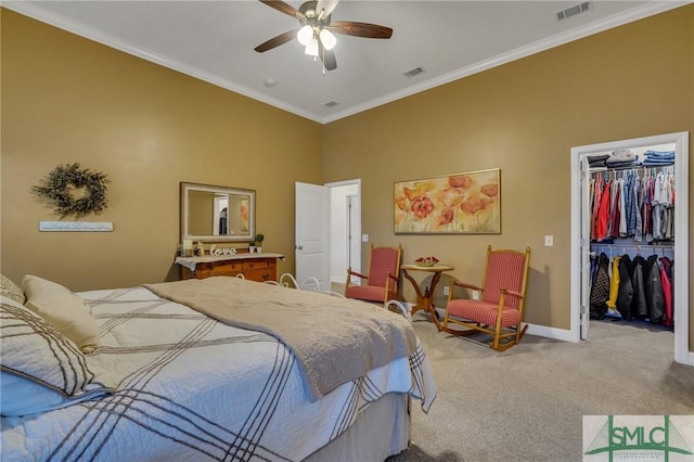 carpeted bedroom featuring a walk in closet, a closet, ornamental molding, and ceiling fan