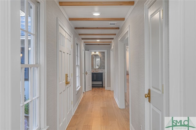 hallway with beamed ceiling, light hardwood / wood-style flooring, and a wealth of natural light