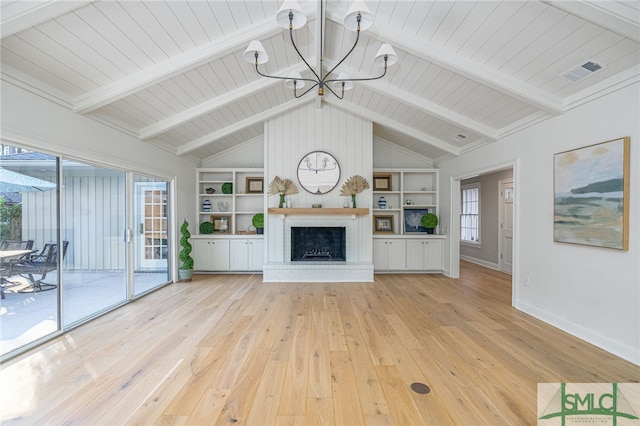 unfurnished living room with light hardwood / wood-style flooring, a brick fireplace, vaulted ceiling with beams, built in shelves, and a notable chandelier