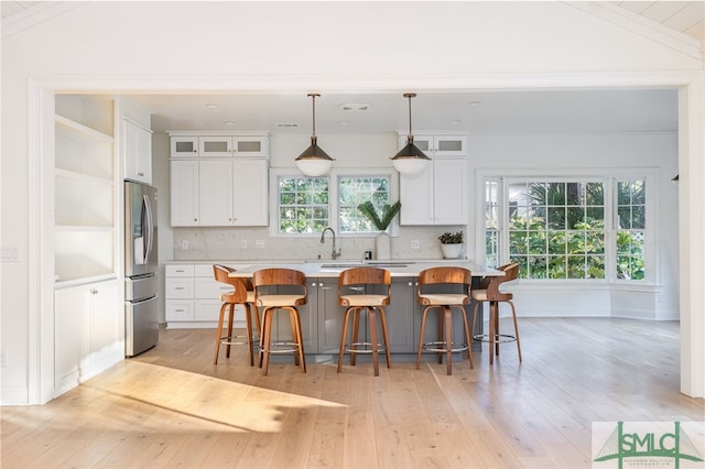 kitchen featuring a kitchen bar, a center island, white cabinets, and stainless steel refrigerator with ice dispenser