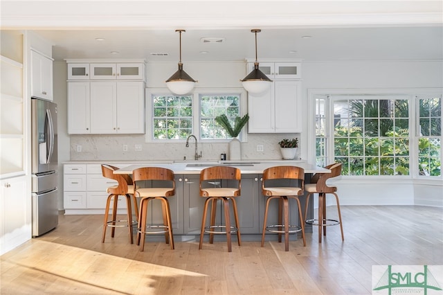 kitchen featuring stainless steel fridge, a kitchen island, a kitchen bar, and white cabinetry