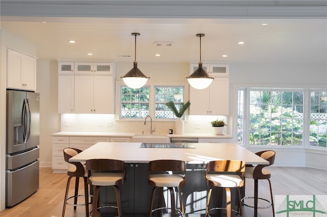 kitchen featuring white cabinets, stainless steel appliances, a kitchen island, and sink