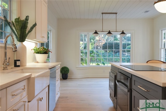 kitchen featuring white cabinetry, sink, pendant lighting, black electric cooktop, and light wood-type flooring