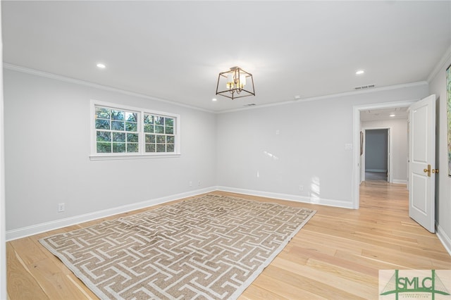 spare room with hardwood / wood-style flooring, crown molding, and a chandelier