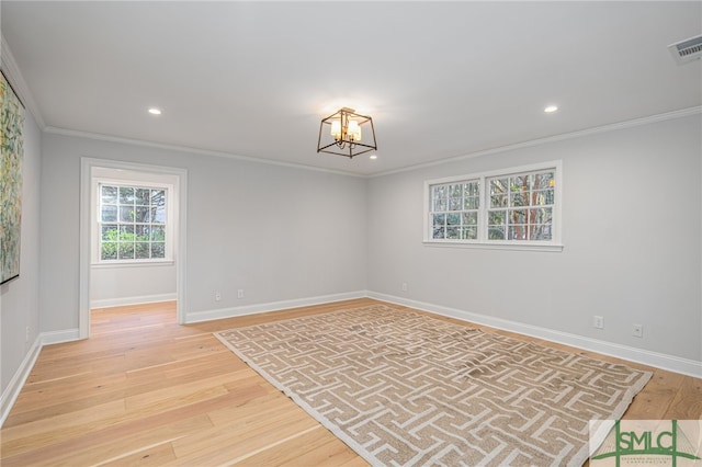 spare room with a chandelier, light wood-type flooring, and ornamental molding