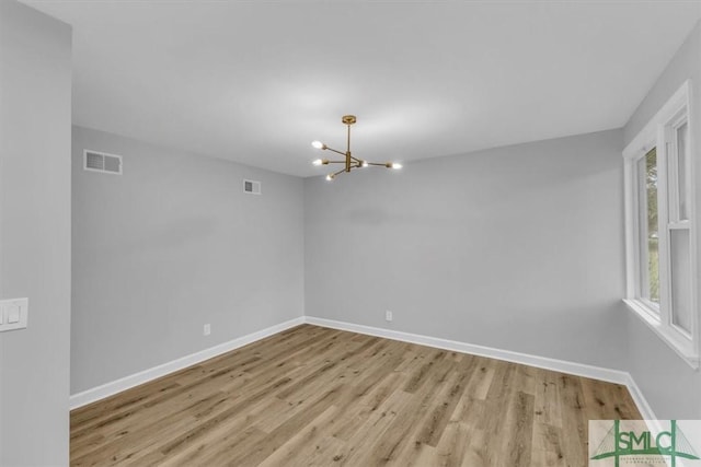 unfurnished room featuring light hardwood / wood-style floors and a notable chandelier