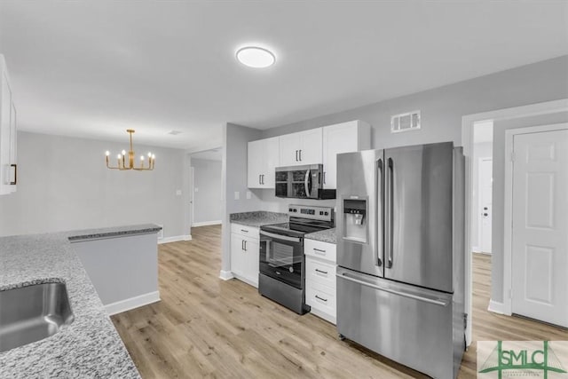 kitchen featuring light hardwood / wood-style flooring, appliances with stainless steel finishes, white cabinetry, hanging light fixtures, and light stone counters