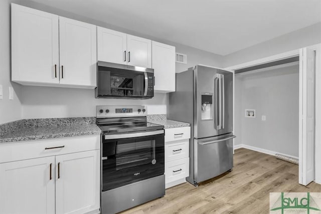 kitchen featuring light stone countertops, white cabinetry, light wood-type flooring, and appliances with stainless steel finishes