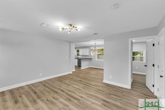 unfurnished living room featuring light hardwood / wood-style flooring, a wealth of natural light, and a chandelier