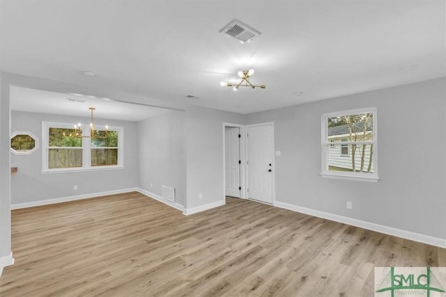 spare room with light wood-type flooring and an inviting chandelier