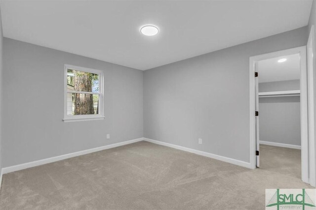 unfurnished bedroom with light carpet, a spacious closet, and a closet