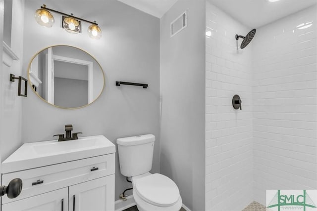 bathroom featuring vanity, toilet, and tiled shower