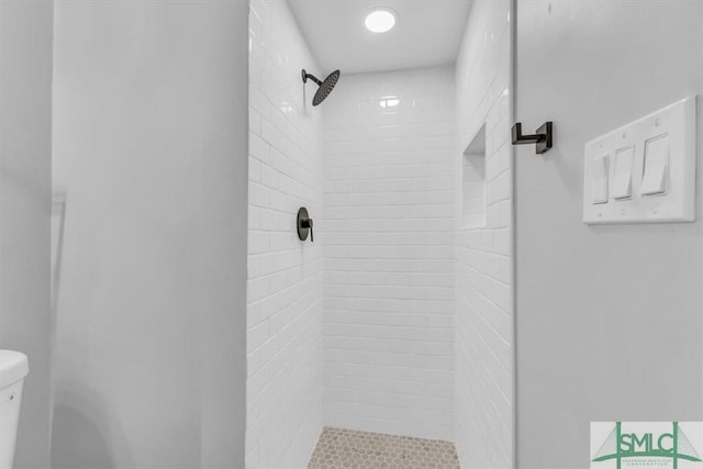 bathroom featuring a tile shower and toilet