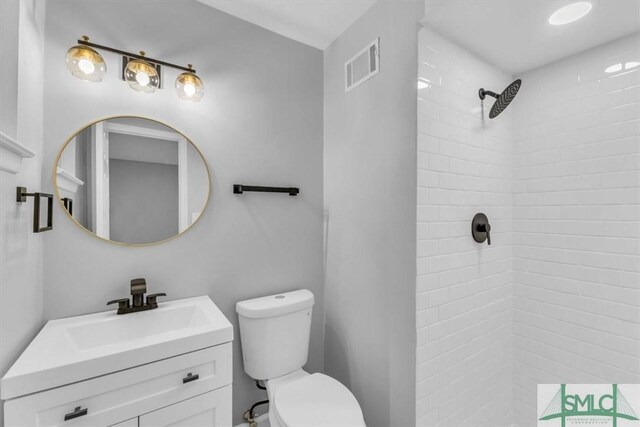 bathroom featuring tiled shower, vanity, and toilet