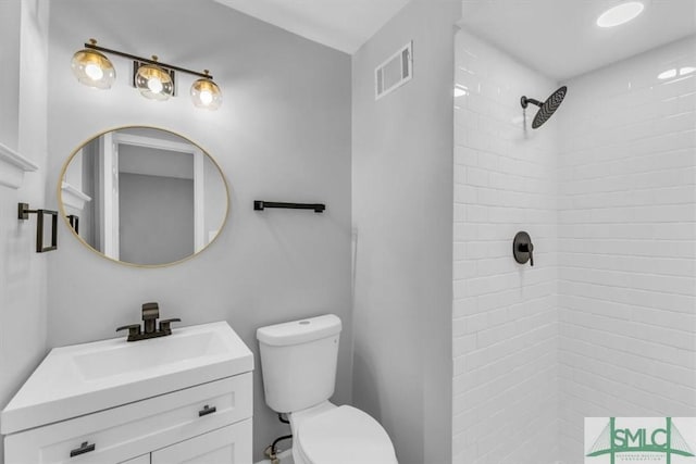 bathroom with vanity, toilet, and a tile shower