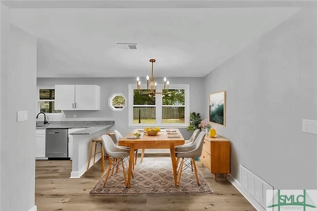 dining space with breakfast area, sink, light hardwood / wood-style flooring, and a chandelier