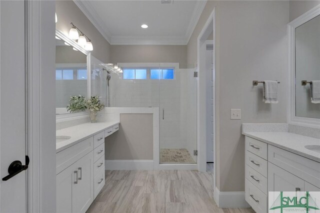 bathroom featuring vanity, a shower with shower door, and ornamental molding