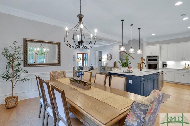 dining room with light hardwood / wood-style floors, ornamental molding, sink, beamed ceiling, and a chandelier