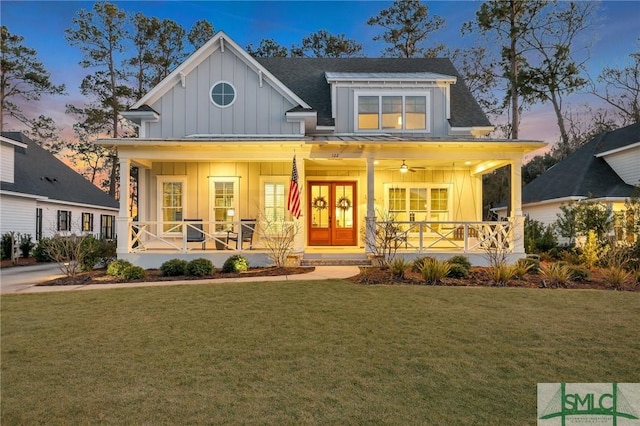 view of front of property with a porch, a yard, and french doors