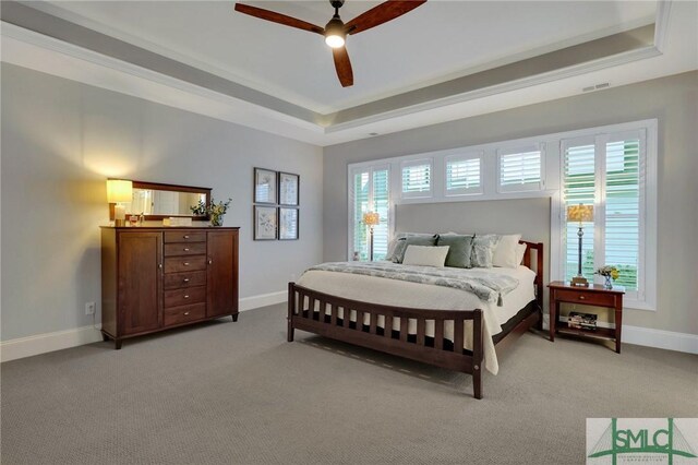 bedroom featuring a tray ceiling, ceiling fan, light carpet, and ornamental molding